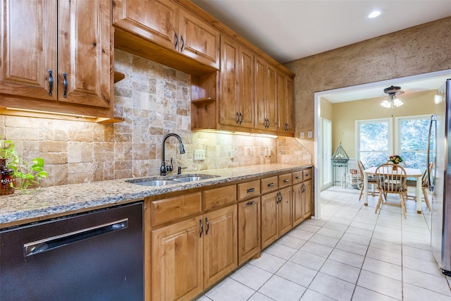 kitchen with a sink, tasteful backsplash, black dishwasher, freestanding refrigerator, and light tile patterned floors