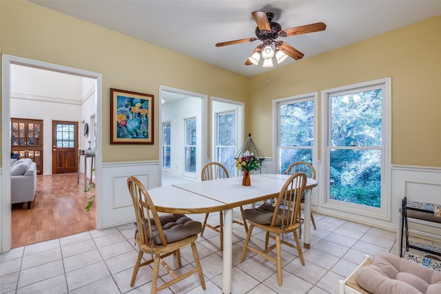 dining area with ceiling fan, light tile patterned floors, and wainscoting