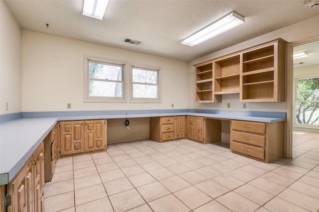 unfurnished office with light tile patterned floors, visible vents, built in desk, and a textured ceiling