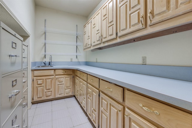 kitchen with a sink, light countertops, light tile patterned floors, and light brown cabinetry