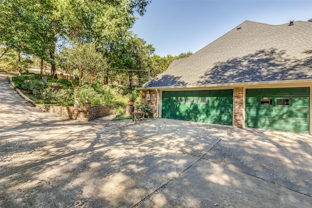 view of home's exterior with a garage, brick siding, and roof with shingles