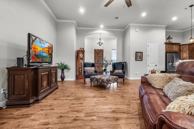 living room with ceiling fan with notable chandelier, ornamental molding, and light hardwood / wood-style flooring