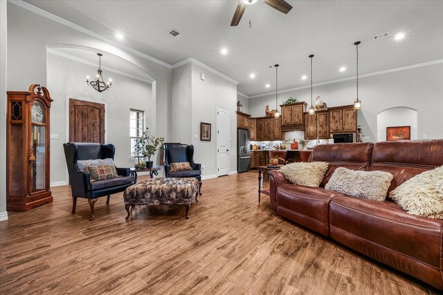 living room featuring light hardwood / wood-style floors, ceiling fan with notable chandelier, and ornamental molding