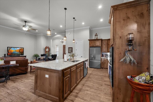 kitchen featuring appliances with stainless steel finishes, pendant lighting, sink, an island with sink, and light hardwood / wood-style floors