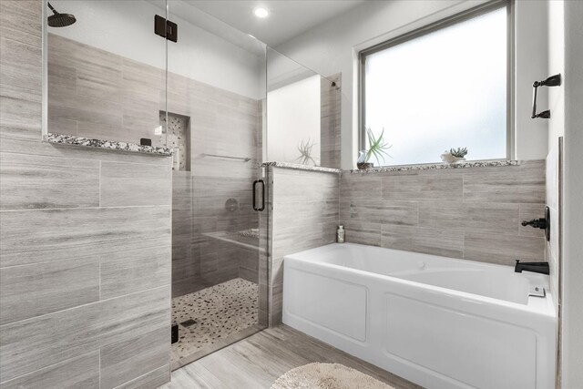 bathroom with independent shower and bath, tile walls, and wood-type flooring