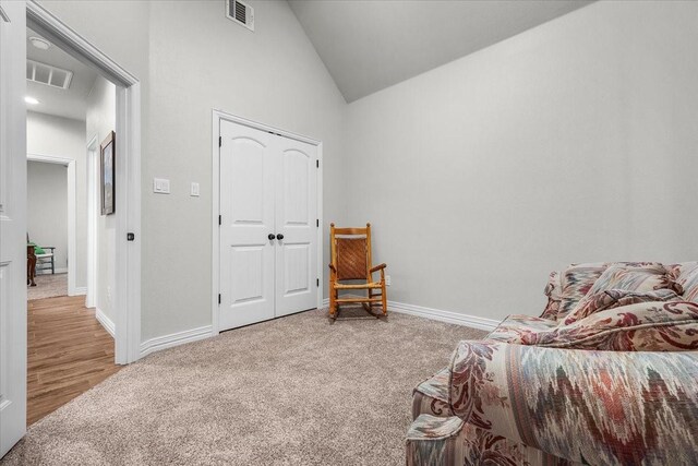 living area featuring carpet and vaulted ceiling