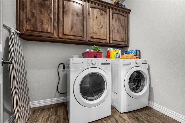 laundry area with dark wood-type flooring, cabinets, and washer and dryer