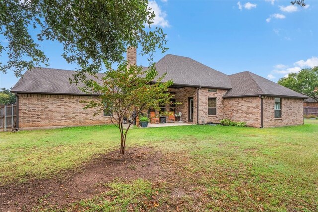 back of house with a lawn and a patio