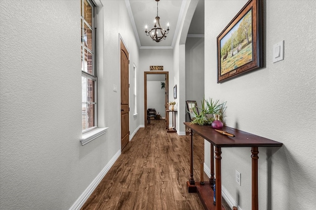 hall with dark wood-type flooring, an inviting chandelier, and ornamental molding