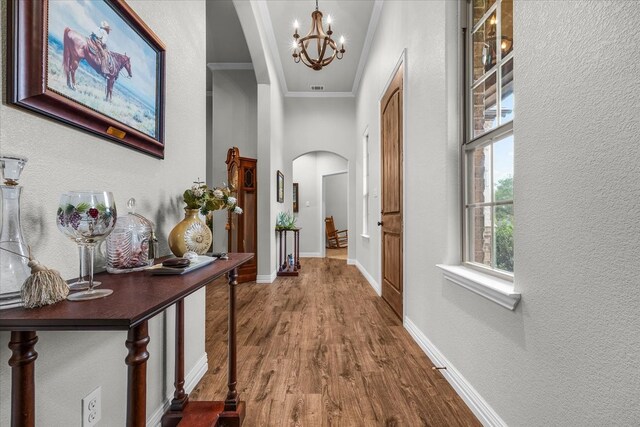 hall with a chandelier, hardwood / wood-style flooring, and ornamental molding