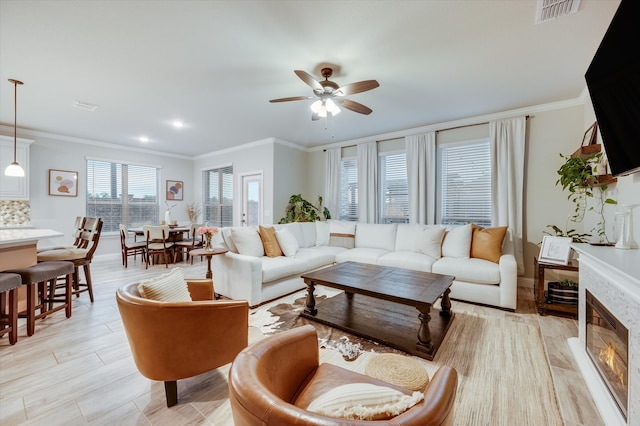 living room with a fireplace, ceiling fan, and crown molding