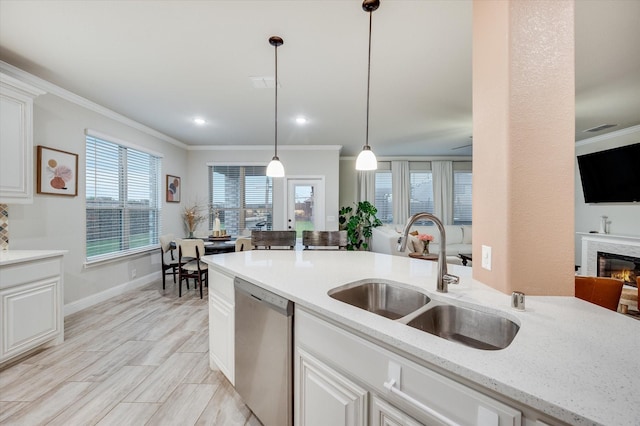 kitchen with decorative light fixtures, sink, white cabinets, stainless steel dishwasher, and light stone countertops