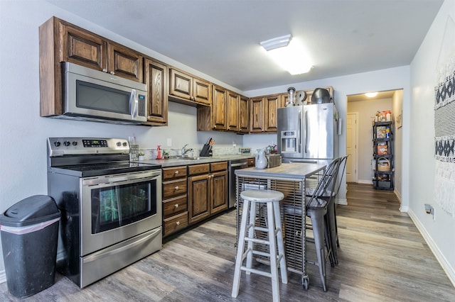 kitchen with a kitchen bar, light hardwood / wood-style floors, sink, and appliances with stainless steel finishes