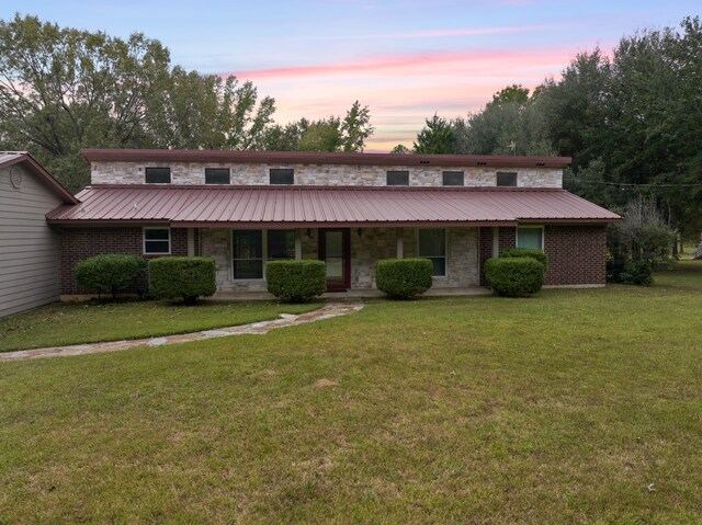 view of front of property featuring a yard, an outdoor structure, covered porch, and a garage