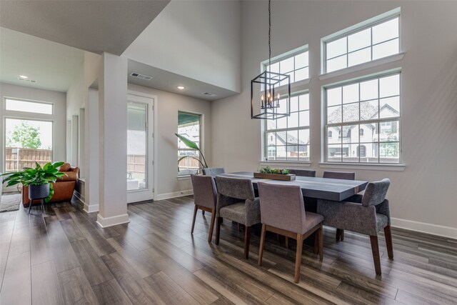 dining area featuring dark hardwood / wood-style flooring, a towering ceiling, and a chandelier