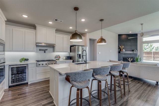 kitchen with pendant lighting, stainless steel appliances, beverage cooler, and white cabinets