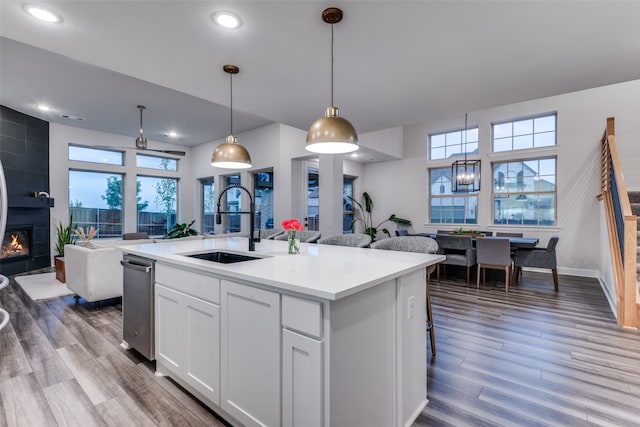 kitchen featuring sink, white cabinetry, decorative light fixtures, hardwood / wood-style floors, and a kitchen island with sink