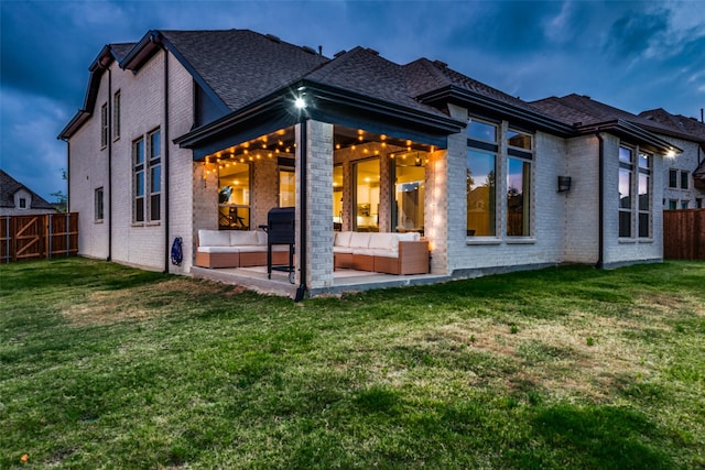 back house at dusk with an outdoor hangout area, a yard, and a patio area