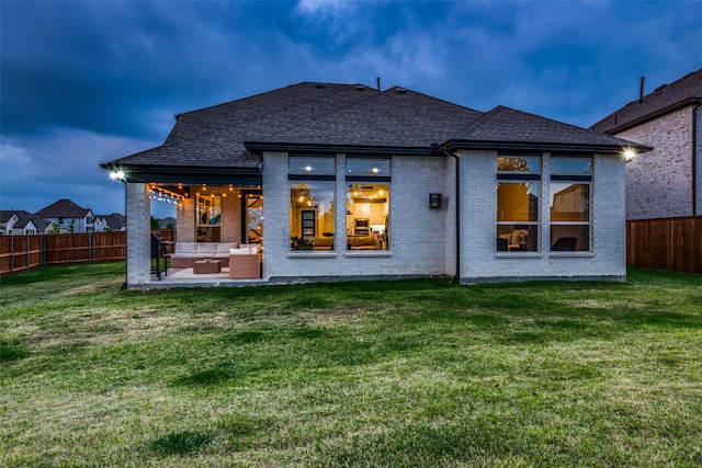 back house at dusk featuring an outdoor hangout area, a yard, and a patio area