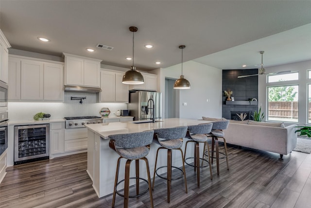 kitchen with stainless steel appliances, white cabinets, beverage cooler, and decorative light fixtures