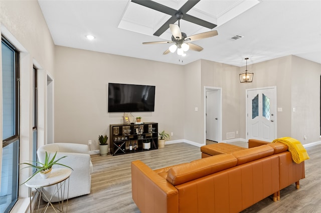 living room featuring ceiling fan with notable chandelier, light hardwood / wood-style floors, and a skylight