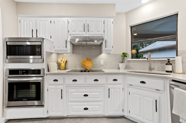 kitchen featuring white cabinets, decorative backsplash, sink, light tile patterned floors, and appliances with stainless steel finishes