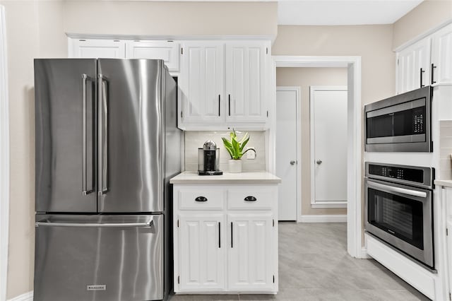 kitchen featuring stainless steel appliances, white cabinetry, light tile patterned floors, and tasteful backsplash