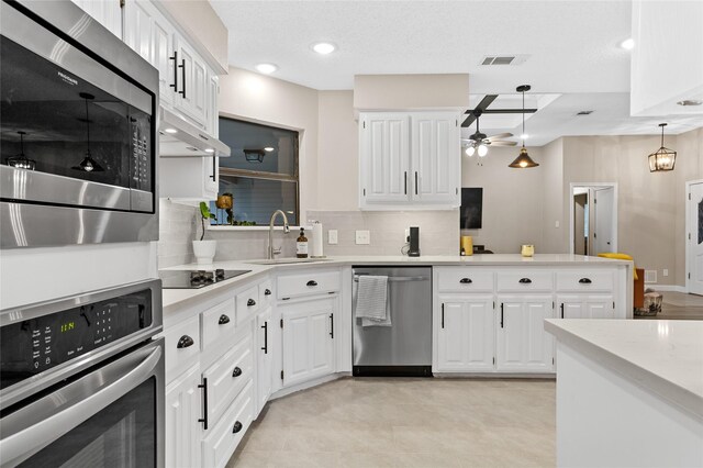 kitchen featuring white cabinets, sink, backsplash, appliances with stainless steel finishes, and decorative light fixtures