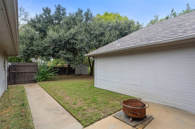 view of yard featuring a storage shed, a fire pit, and a patio area