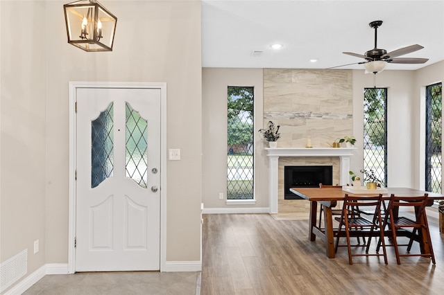 entrance foyer with a fireplace, ceiling fan, and light wood-type flooring