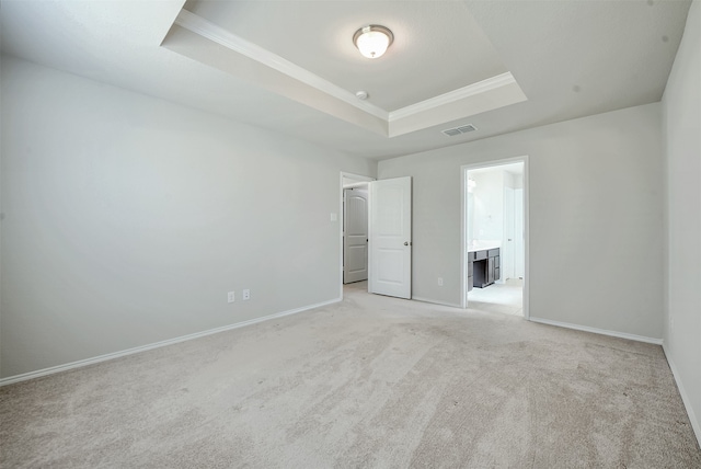 unfurnished bedroom with ensuite bath, ornamental molding, a raised ceiling, and light carpet