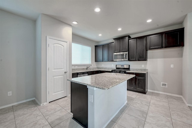 kitchen with sink, a center island, light tile patterned floors, stainless steel appliances, and light stone countertops