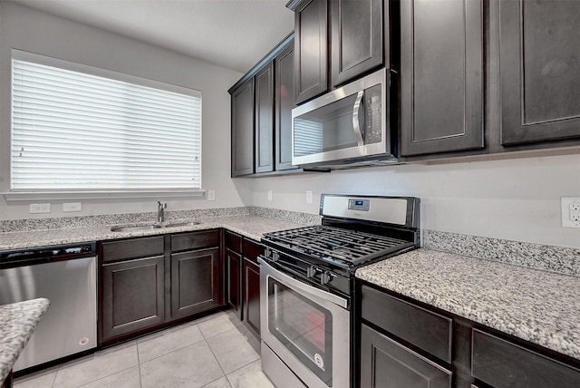 kitchen with stainless steel appliances, dark brown cabinets, sink, and light tile patterned floors