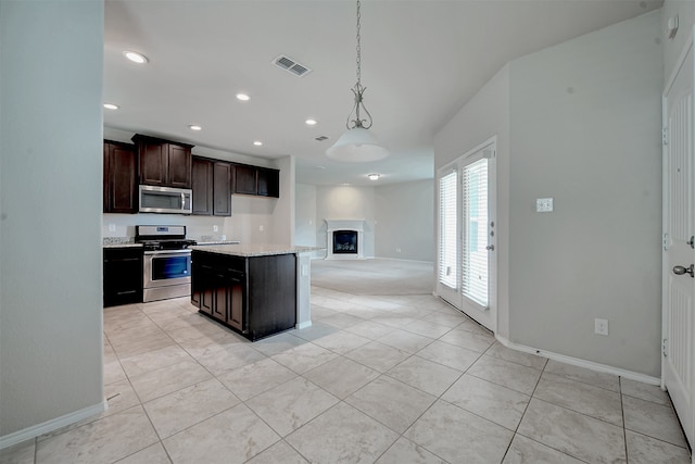 kitchen featuring pendant lighting, a center island, light stone countertops, dark brown cabinets, and appliances with stainless steel finishes