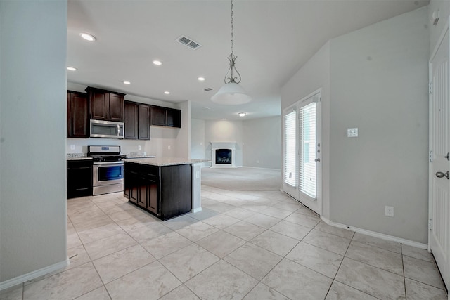 kitchen with stainless steel appliances, a center island, dark brown cabinetry, light stone countertops, and decorative light fixtures