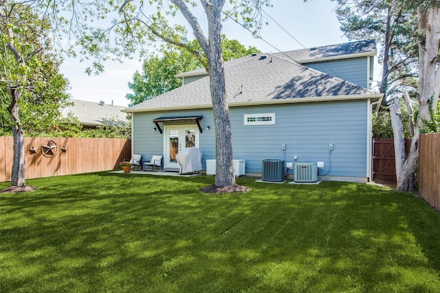 rear view of house featuring cooling unit and a yard