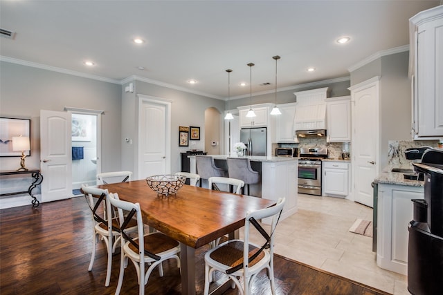 dining space with ornamental molding and light hardwood / wood-style flooring