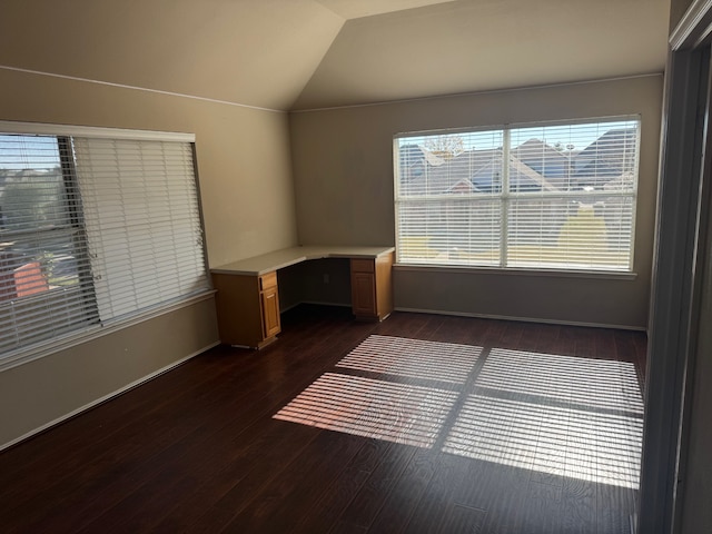 unfurnished room with dark wood-type flooring, built in desk, and vaulted ceiling