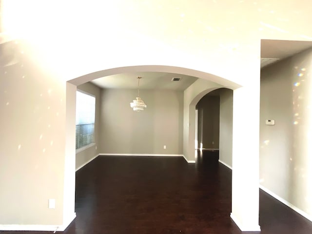 empty room featuring dark hardwood / wood-style floors and a notable chandelier