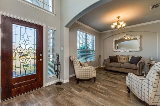 foyer with wood-type flooring, a chandelier, and ornamental molding