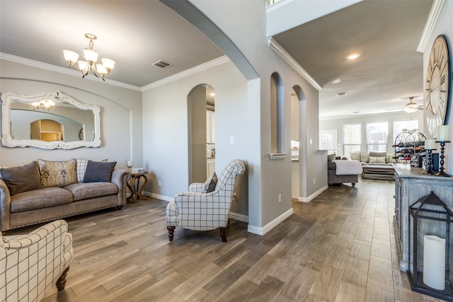 living room with ornamental molding, hardwood / wood-style floors, and ceiling fan with notable chandelier