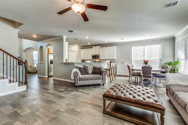 living room with ornamental molding, hardwood / wood-style floors, and ceiling fan