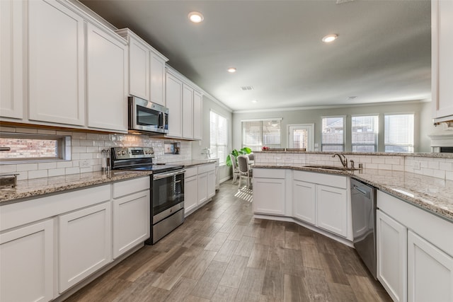 kitchen featuring dark hardwood / wood-style flooring, white cabinets, tasteful backsplash, ornamental molding, and appliances with stainless steel finishes