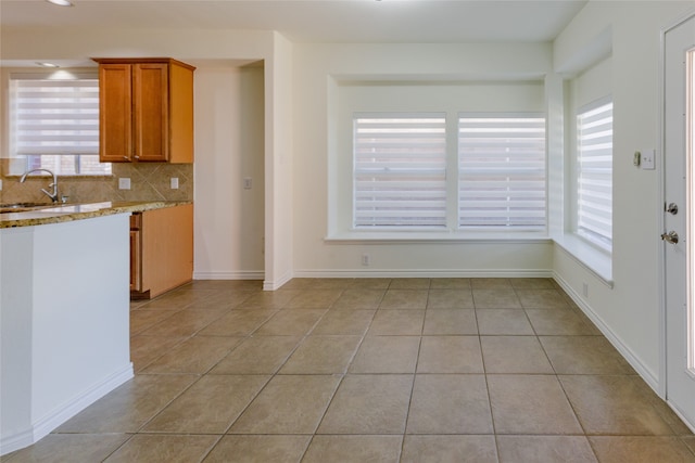 kitchen featuring backsplash, sink, light stone counters, and light tile patterned flooring