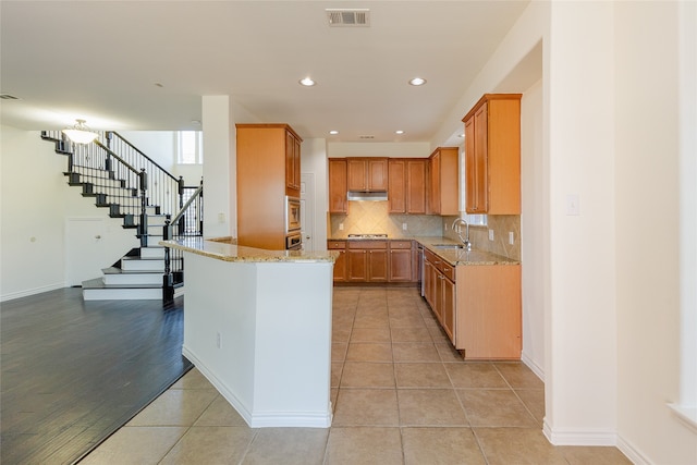 kitchen with decorative backsplash, light stone countertops, sink, and light tile patterned floors