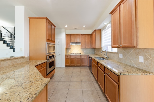 kitchen with stainless steel appliances, light tile patterned flooring, sink, light stone countertops, and decorative backsplash