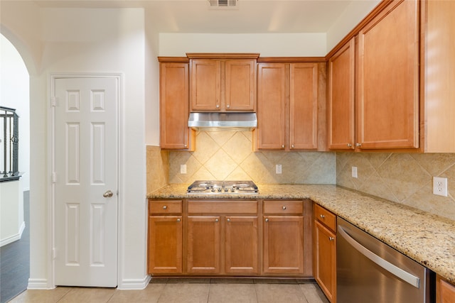 kitchen with stainless steel appliances, light tile patterned floors, light stone counters, and backsplash