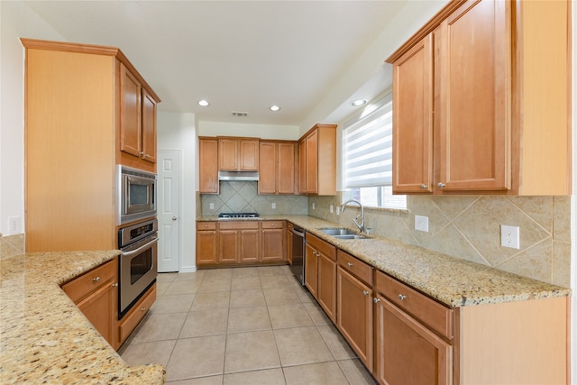 kitchen with stainless steel appliances, light tile patterned flooring, sink, light stone counters, and tasteful backsplash