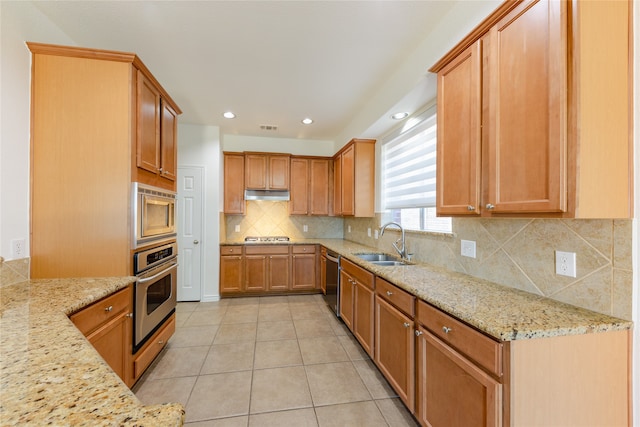 kitchen featuring stainless steel appliances, light stone counters, sink, light tile patterned floors, and backsplash