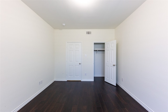 unfurnished bedroom with dark wood-type flooring and a closet